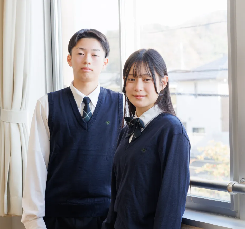 総合学科の男女の生徒が窓を背景に笑顔で並んでいる様子