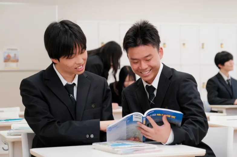 教室で学生同士が教科書を一緒に見ながら、内容を確認し合って学習している様子