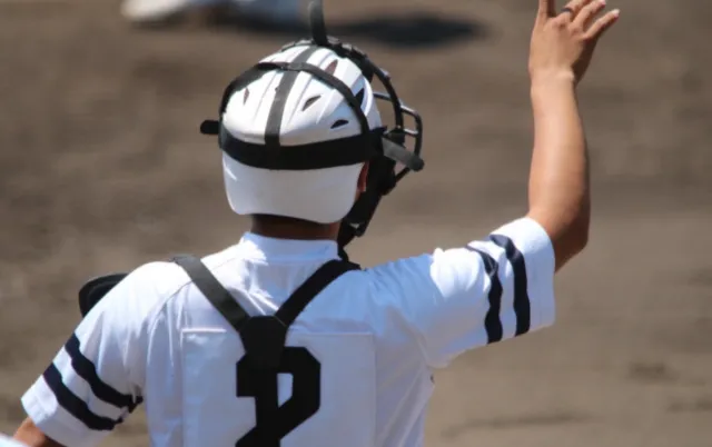 野球場で、キャッチャーが片手を挙げて合図をしている様子