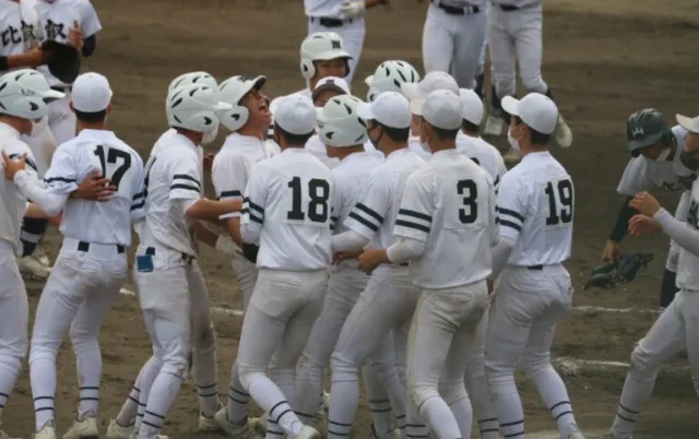 野球場で、複数の野球部員がグラウンドに集まっている様子