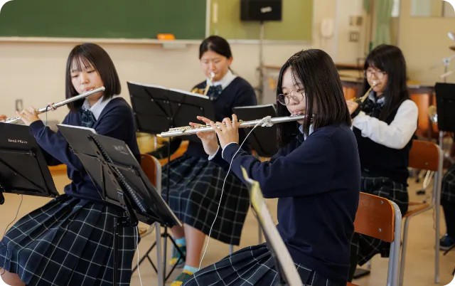 教室でフルートを演奏し、合奏練習を行っている部員の様子