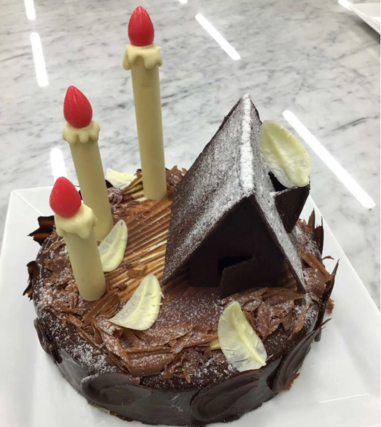 チョコレートケーキの上にキャンドル型の飾りとチョコレート細工をあしらったデコレーションケーキ