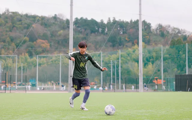 サッカー部の部員が屋外グラウンドでボールを蹴っている様子