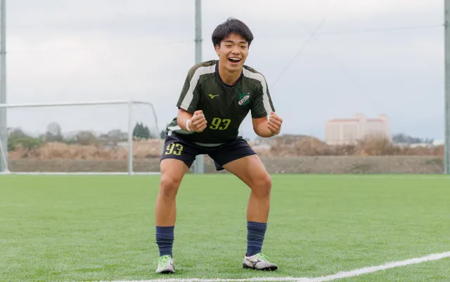 サッカー部の部員が屋外グラウンドでガッツポーズをとっている様子