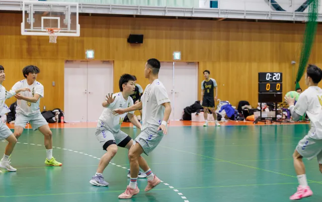 屋内の体育館で、ハンドボール部の部員がパスをしている様子