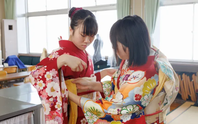 部員が浴衣を着た別の部員の帯を丁寧に整えている様子