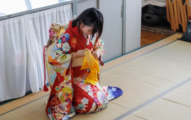 畳の上に座り、帯を手にして結びの準備をしている部員の様子