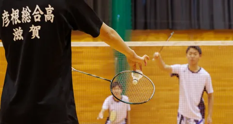 バドミントン部で、ラケットを使ってシャトルを打つ様子