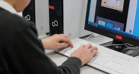 コンピュータ部で、パソコンのキーボードを操作して作業している様子
