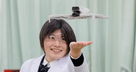 白衣と保護ゴーグルを着用した生徒が、実験用の装置を使っている様子