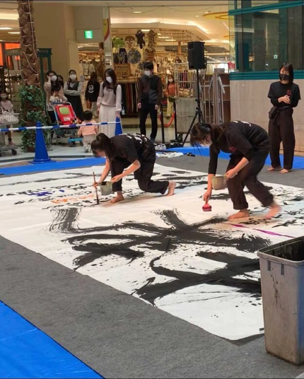 ショッピングモールで、部員が大きな紙に揮毫している様子