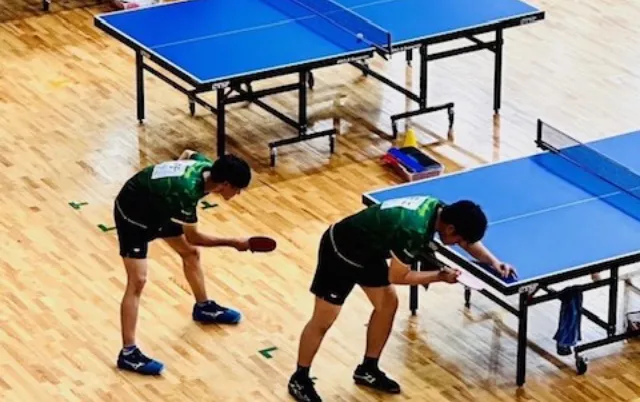 ダブルスの試合でサーブを打とうとしている部員