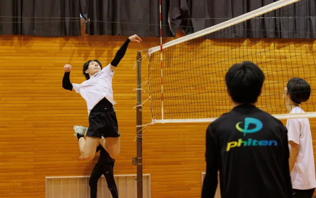バレーボール部の部員がネット前でプレーしている様子