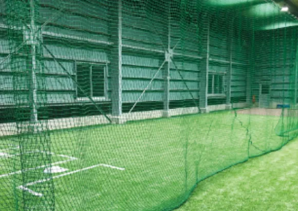 人工芝の床と防球ネットが設置された室内グラウンド